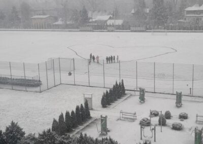 uczniowie na boisku szkolnym pokrytym śniegiem