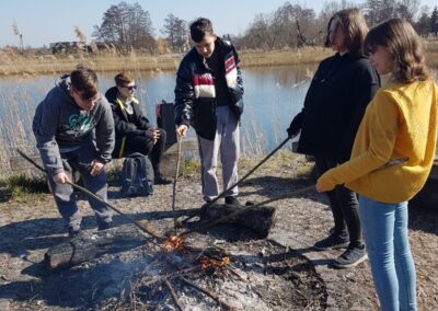 uczniowie smażą kiełbaski na ognisku